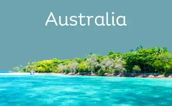 Scenic view of a tropical beach with clear turquoise water in the foreground and lush green vegetation along the shoreline, under a clear sky, with the word Australia at the top